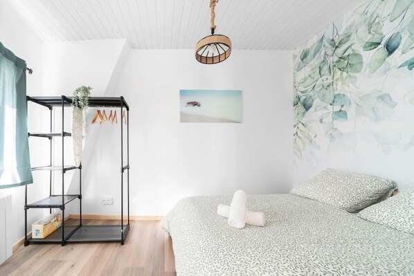 A bedroom with a bed, a wall-mounted shelf with a plant, a painting, and a ceiling light fixture. - Le Nature - 2 allée Berthomier - Cusset (Cusset)
