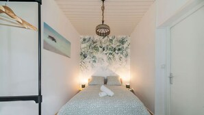 Une chambre à coucher avec un lit, un tableau, un luminaire suspendu et une porte.