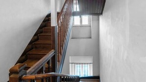 Un escalier en bois avec une rampe métallique menant à un palier.