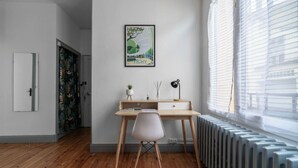 Une chambre moderne avec un plancher en bois, un bureau avec une chaise, un radiateur et une fenêtre avec des stores.