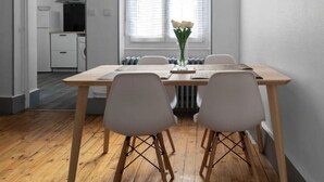 Une cuisine moderne avec des meubles blancs, un réfrigérateur noir et une fenêtre équipée de stores.