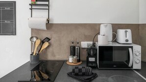 Eine Küchenzeile mit einer Mikrowelle, einem Toaster, einer Kaffeemaschine und einem kleinen Hängeschrank mit Küchenpapier.