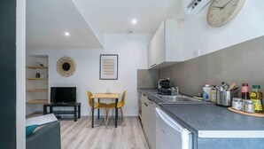 A compact kitchen with a dining area, a TV, and a clock on the wall. - Air-cond duplex apartment in the city center (Vichy)