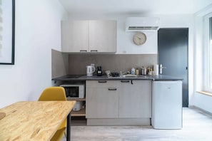 A compact kitchen with a microwave, kettle, coffee maker, and refrigerator.