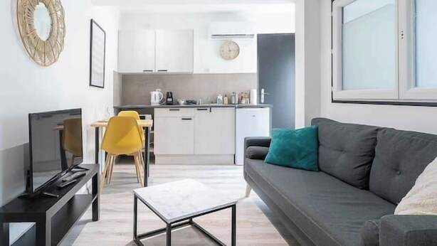 A modern living room with a sofa, a coffee table, a TV, and a dining area with chairs. - Air-cond duplex apartment in the city center (Vichy)