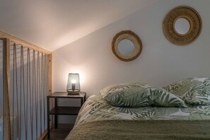 Une chambre à coucher comprenant un lit, une table de chevet avec une lampe, un mur recouvert de lambris en bois et deux miroirs fixés au mur.