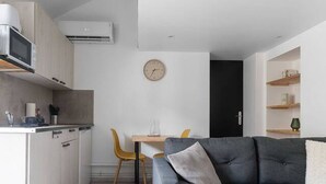 A modern kitchen with white cabinets, a microwave, and an air conditioning unit. - Air-cond duplex apartment in the city center (Vichy)