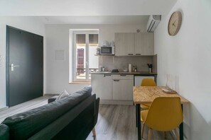 Une cuisine compacte équipée d’un four à micro-ondes, de placards et d’un coin repas avec une table et des chaises.