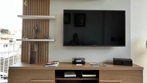 Ein modernes Wohnzimmer mit einer Holz-Unterhaltungseinheit, einem flachbildfernseher an der Wand und einer kleinen Pflanze auf der Einheit.