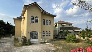 A two-story building with a symmetrical facade, large windows, and a gated entrance. - 1 Bed - Sleeps 4 - Parking - 5 Min to Beach (Ocho Rios)