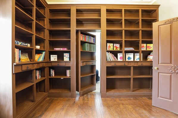 A library with wooden bookshelves, a door, and a person in the background.