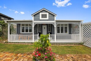 A two-story house with a porch, a small garden with flowers, and a brick pathway.