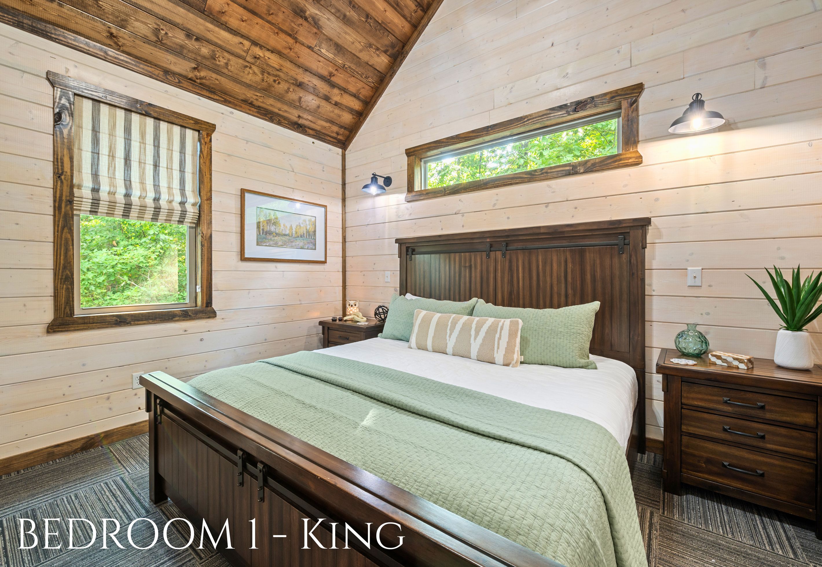 A wooden-paneled bedroom with a bed, bedside tables, a window with a view, and a small skylight.
