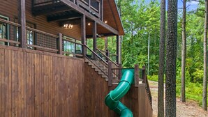 Une cabane en bois avec un toboggan vert fixé à la paroi extérieure.