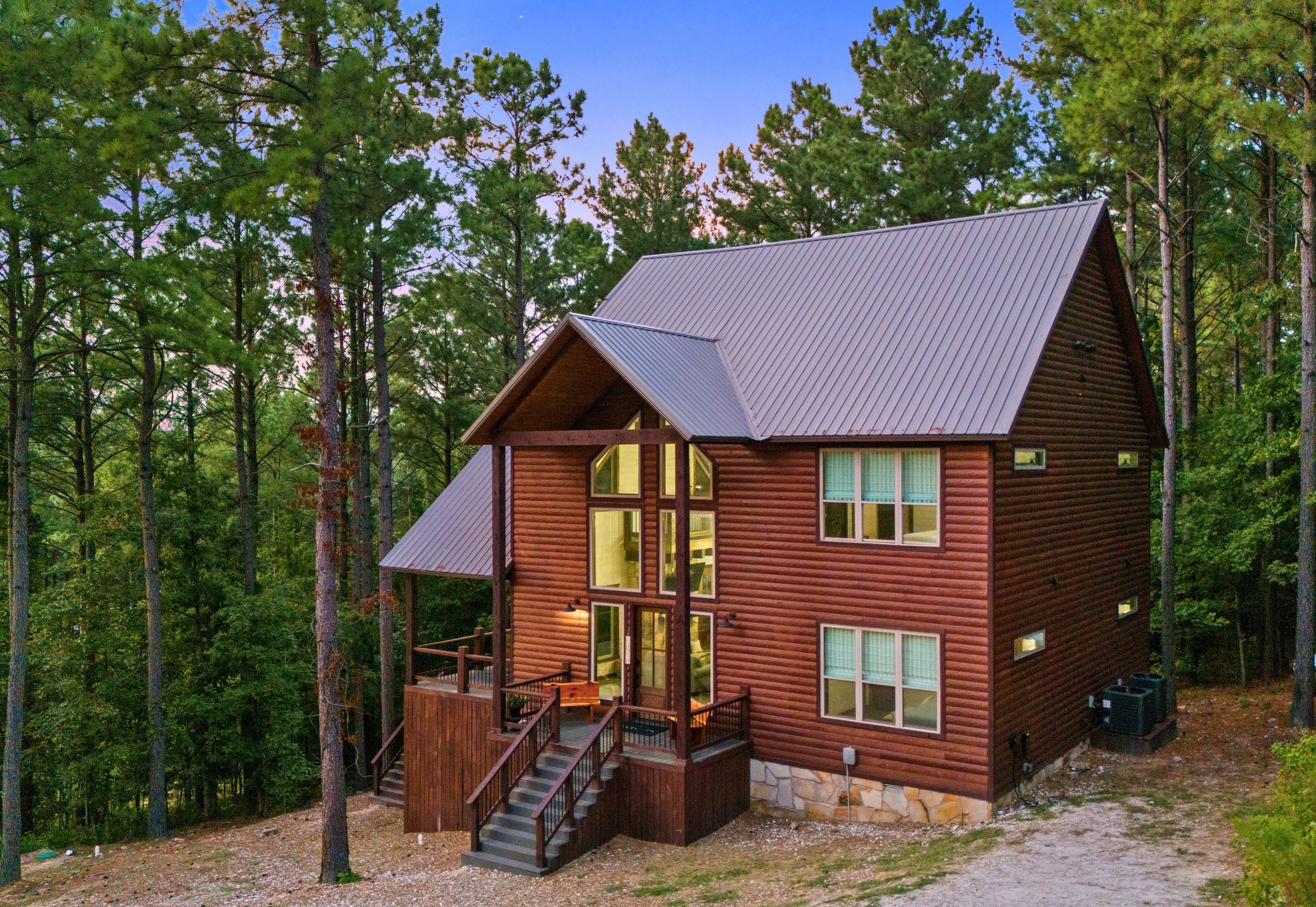 A cabin with a porch, a staircase, and a stone foundation.