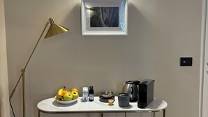 A neatly organized workspace with a desk, a standing lamp, a framed picture, and a small table with fruits and a kettle. - B&B Genova Holiday (Genoa)