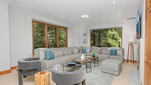 A modern living room with a sectional sofa, two armchairs, a coffee table, and a wooden stool. - Liftside C22 | Ski-In/Ski-Out 3BR at Cascade Village (Vail)