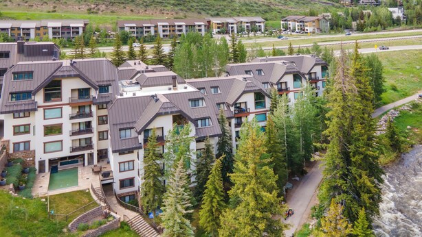 A multi-story hotel with balconies, a swimming pool, and a view of a river. - Liftside C22 | Ski-In/Ski-Out 3BR at Cascade Village (Vail)