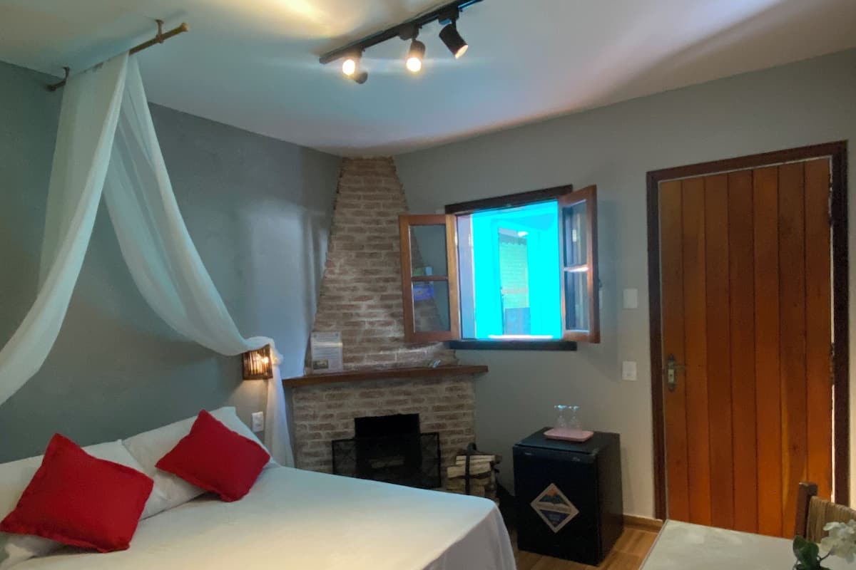 Une chambre à coucher avec un lit, une cheminée, une table et une chaise.