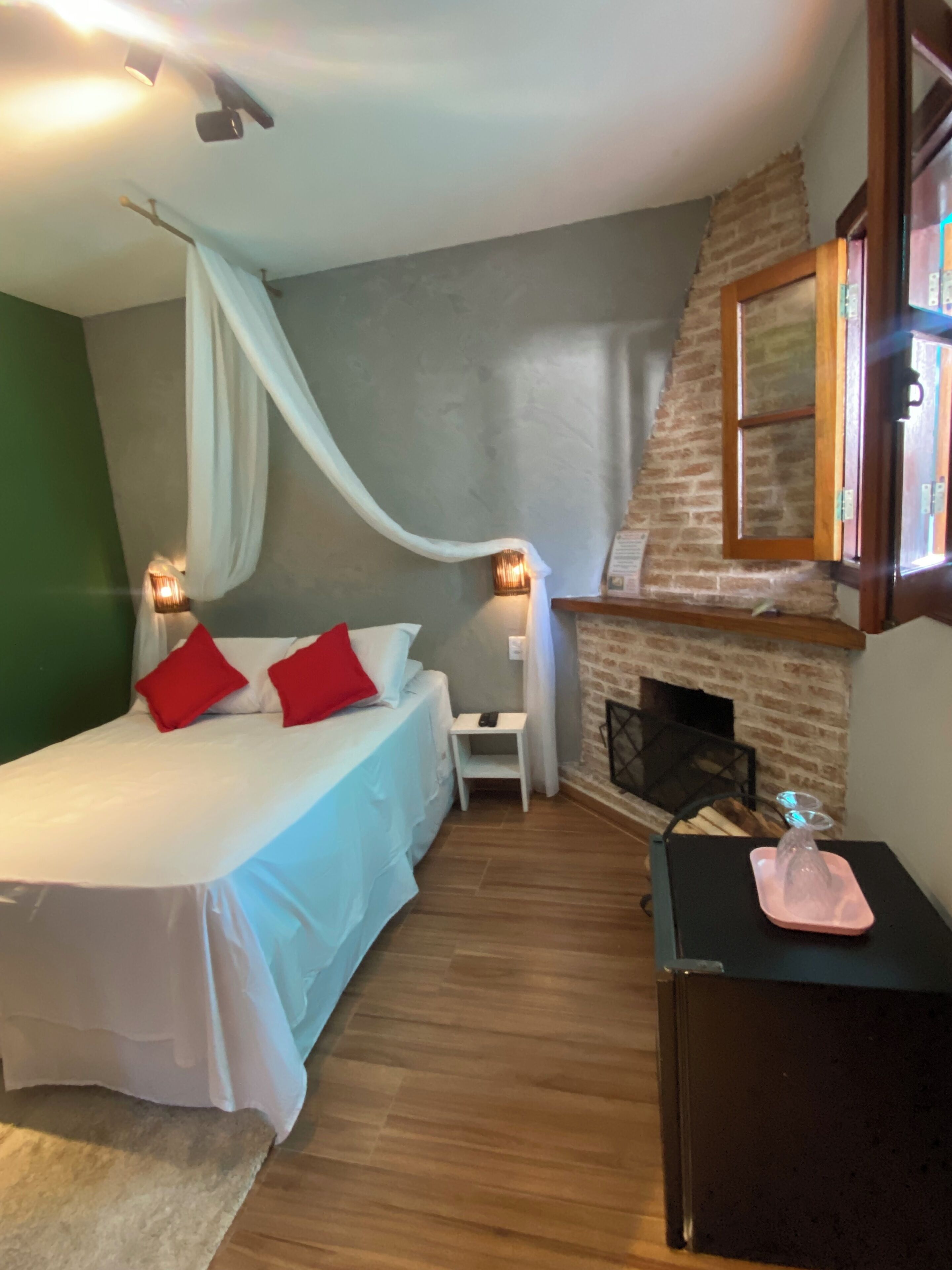Une chambre à coucher avec un lit, une petite table, une chaise, une cheminée et une table de chevet.
