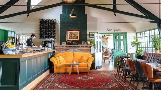 A spacious interior with a high ceiling, a central seating area with a yellow sofa, a bar area, and a dining section. - Central Ellesmere -sleeps2 - Parking - Petfriendly (Ellesmere)