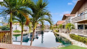 A resort with a swimming pool, palm trees, and modern buildings. - Lovely 2 Bedroom Lake View Home on Siesta Key! (Siesta Key)