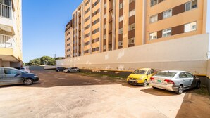 A parking area with multiple cars, a building with a beige facade, and a clear sky.