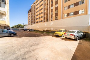 A parking area with multiple cars, a building with a beige facade, and a clear sky.