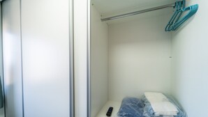 A hotel room with a closed door, a small table with a remote control, and a plastic bag containing folded clothes.