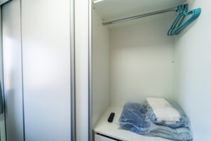 A hotel room with a closed door, a small table with a remote control, and a plastic bag containing folded clothes.