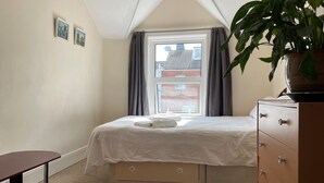 A bedroom with a bed, a dresser, a desk, and a window with curtains. - St Michael's Holiday Home (Bournemouth)