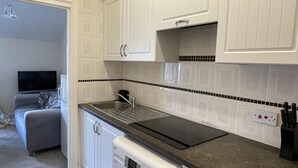 A compact kitchen with white cabinets, a built-in microwave, and a dishwasher. - St Michael's Holiday Home (Bournemouth)