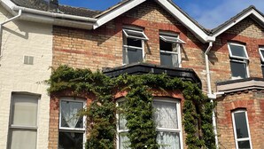 A two-story house with a brick facade, multiple windows, and a chimney. - St Michael's Holiday Home (Bournemouth)