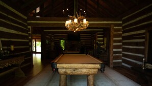 Ein Holzbilliardtisch in einer Blockhütte mit einer Chandelieber.
