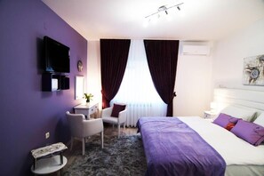 Relax in a stylish room with a made bed, flat-screen TV, and a comfortable chair.