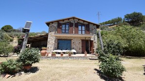 A two-story stone house with a balcony, surrounded by a garden with potted plants and a solar panel. - Villa Roccella Ionica, Sea View, a c (Roccella Ionica)
