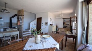 A cozy kitchen with a wooden table, a vase of flowers, and a staircase leading to another room. - Villa Roccella Ionica, Sea View, a c (Roccella Ionica)