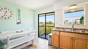 A kitchen with a dining area, a large window, and a view of the neighborhood.