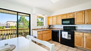 A modern kitchen with wooden cabinets, a black stove, and a microwave.