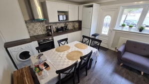 Cocina compacta con comedor, lavadora y sofá.