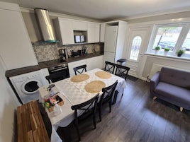 A compact kitchen with a dining area, a washing machine, and a sofa.