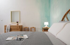 Ein Schlafzimmer mit einem Bett, einem Nachttisch mit Lampe, einer Kommode und einem Spiegel.
