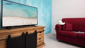 A television on a wooden cabinet, a red sofa, and a blue wall. - Casa Bata by Wonderful Italy (Budoni)