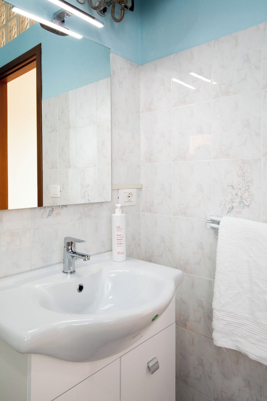 Une salle de bain avec un lavabo blanc, un miroir et un porte-serviettes.