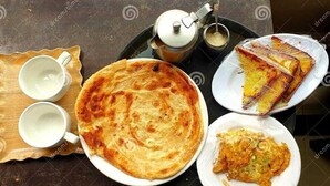 Een maaltijd met platbrood, een gefrituurd gerecht en twee bekers van een witte drank op een dienblad.