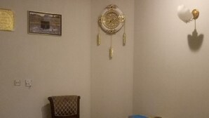 Een kamer met een plafondventilator, een bureau met papieren, een stoel en een wandklok.