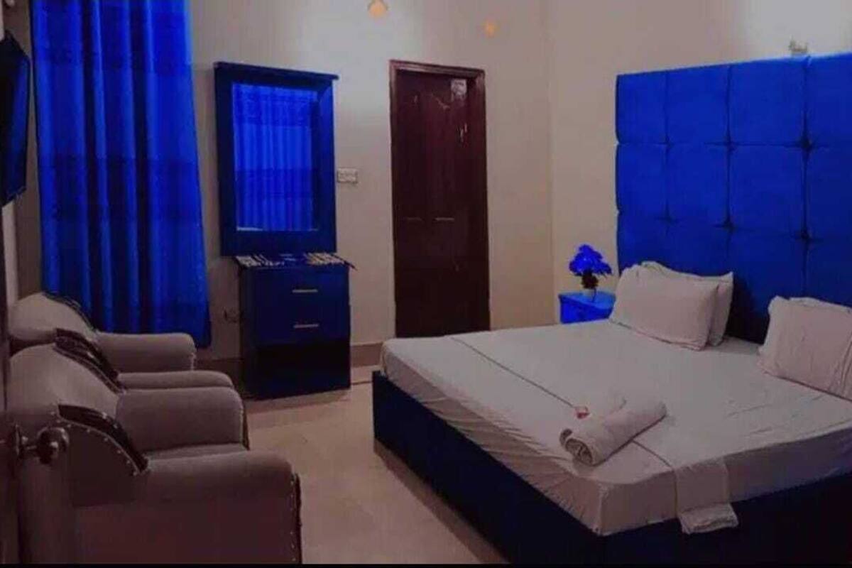 Quarto de hotel com cama, escrivaninha, cadeira, televisão e porta.