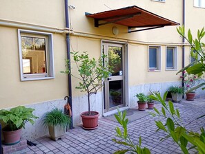 Stunning building with a warm exterior, surrounded by lush greenery and shaded entrance.