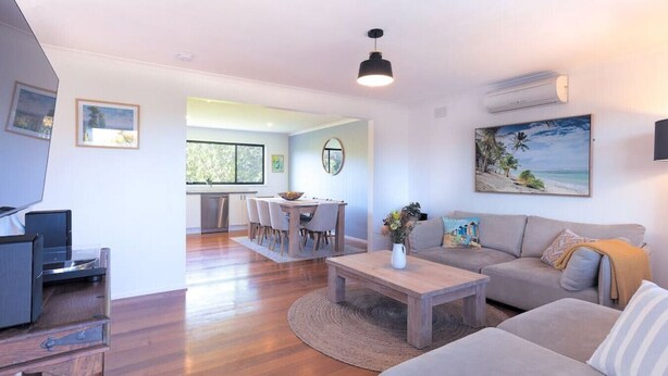 A modern living room with a sofa, coffee table, and a dining area with chairs and a table. - 428 Eastbourne Road · Rosebud Garden Cottage (Capel Sound)