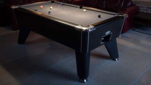 A pool table in a room with wooden walls and ceiling beams, surrounded by red leather seating. - Essitone: Cinema Room, Games Room, Gym & More! (Ashton Keynes)